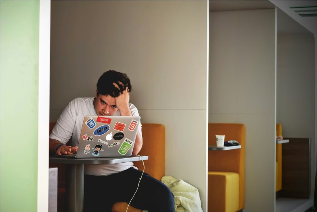 homme portant un haut blanc a laide dun MacBook